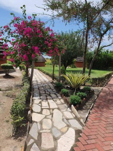 a garden with pink flowers and a stone path at Heritage Safari Lodge in Pakwach East