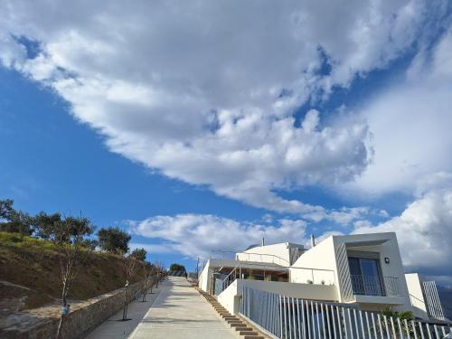 a white building on a beach with a cloudy sky at Physis Fokida in Eratini