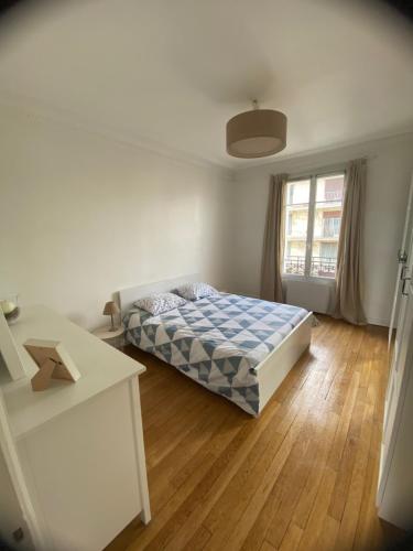 une chambre avec un lit et un parquet dans l'établissement Appartement Saint-Maur-des-Fossés, à Saint-Maur-des-Fossés