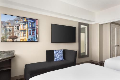 a bedroom with a bed and a couch and a tv at Hilton San Francisco Financial District in San Francisco