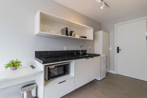 a white kitchen with a sink and a microwave at GO 24 by My Way in Porto Alegre