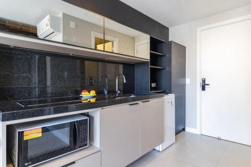 a kitchen with white cabinets and a microwave at GO 24 by My Way in Porto Alegre