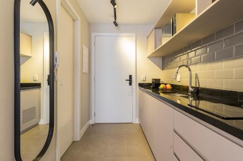a kitchen with a sink and a mirror and a hallway at GO 24 by My Way in Porto Alegre