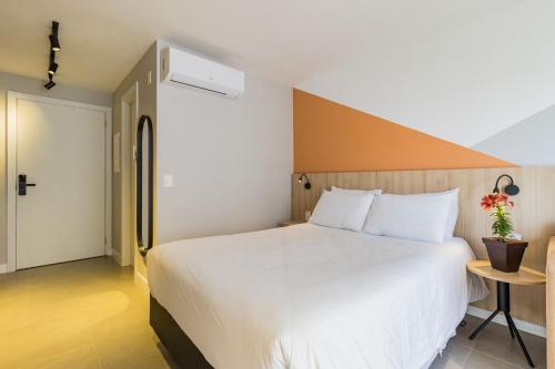 a bedroom with a large white bed and a table at GO 24 by My Way in Porto Alegre