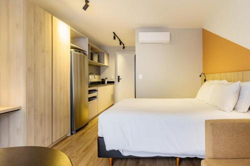 a small bedroom with a bed and a kitchen at GO 24 by My Way in Porto Alegre
