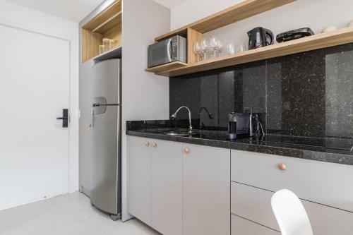 a kitchen with white cabinets and a sink and a refrigerator at GO 24 by My Way in Porto Alegre