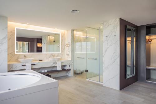 a bathroom with a tub and two sinks and a shower at El Embajador, a Royal Hideaway Hotel in Santo Domingo