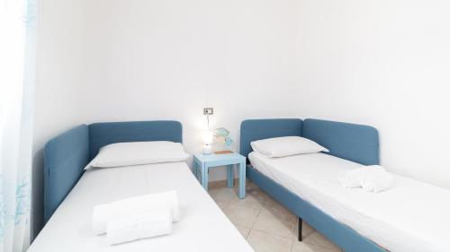 two beds in a room with a side table at Sardinianworld - Casa Dei Bucanieri in Putzu Idu