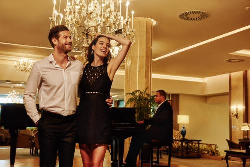 a man and a woman standing in front of a piano at El Embajador, a Royal Hideaway Hotel in Santo Domingo