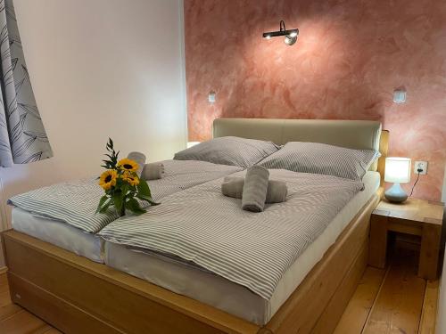 a large bed with a vase of flowers on it at Apartmány HÁJOVNA Lipno in Loučovice