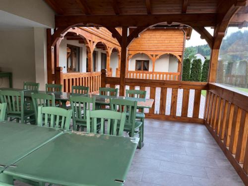 a cafeteria with green tables and chairs on a wooden deck at CABANA ZIMBRU in Băile Borşa