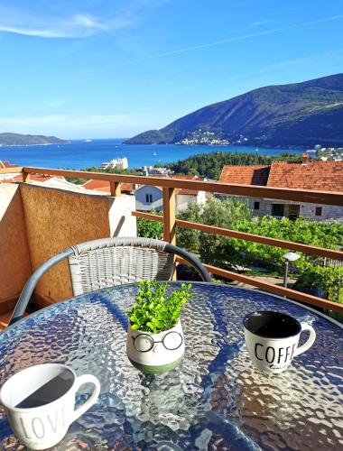 two coffee cups and a plant on a table on a balcony at Durakovic Apartments in Herceg-Novi