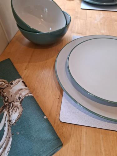 a wooden table with plates and a bowl on it at Luxury Shepherd's Hut - The Hyde in Reading