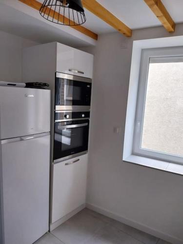 Il comprend une cuisine équipée d'un réfrigérateur et d'une fenêtre. dans l'établissement Appartement cosy et calme, à Saint-Pierre-de-Boeuf
