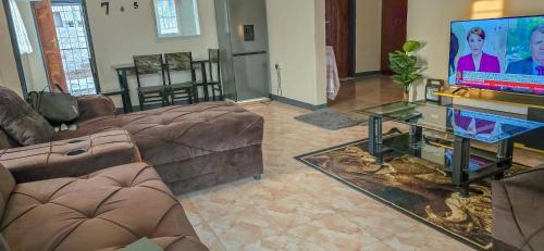 a living room with couches and a flat screen tv at EAGLE WEAVERS NEST in Livingstone