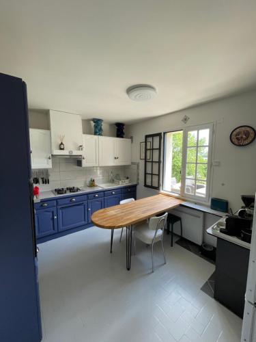 une cuisine avec des placards bleus et une table en bois dans l'établissement Maison vue Rance, à Saint-Samson-sur-Rance