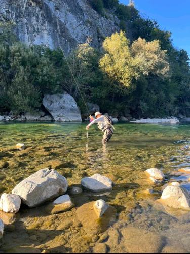 a man standing in the water fishing in a river at Ethno village & resort Ćorić in Mojkovac
