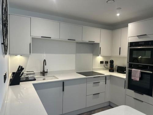 a white kitchen with white cabinets and black appliances at Museum View Apartments City Centre 1 Bedroom in Cardiff