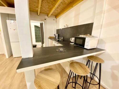 a kitchen with a counter with stools and a microwave at La mezzanine Rouennaise in Rouen