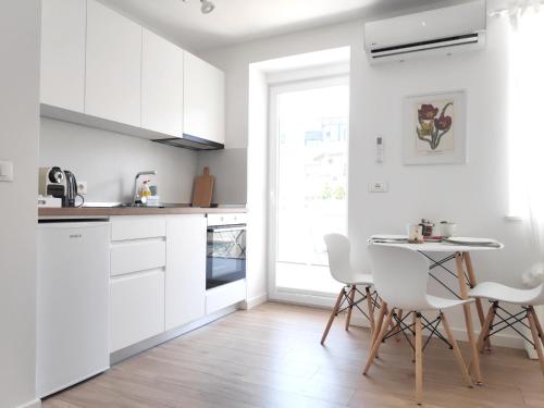 a kitchen with white cabinets and a table and chairs at Te Amantia Apartment in Tirana