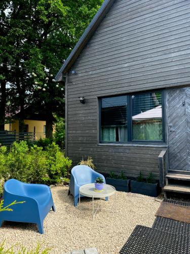a patio with two blue chairs and a table at Amazing little house on an island with garden in Rīga