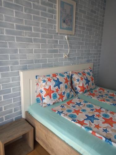 a bed in a room with a brick wall at Мезонет Мени - две спални и две бани in Burgas City