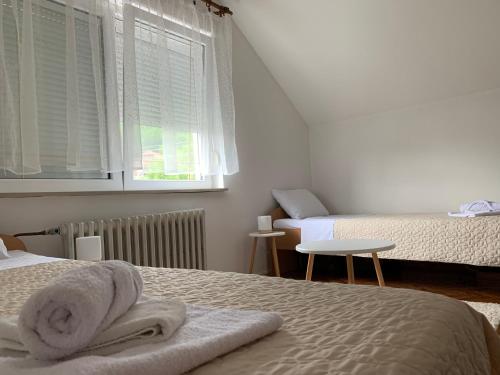 a white bedroom with two beds and a window at Pansion "Dušica" in Bor