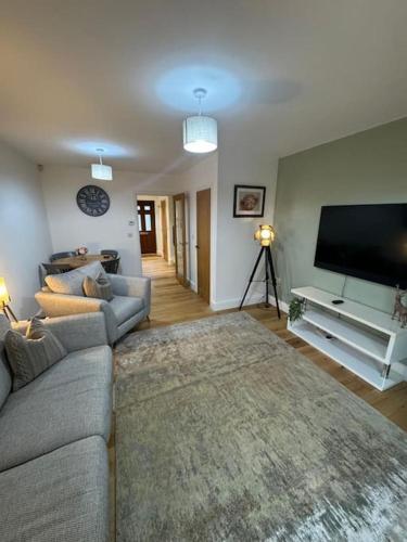a living room with a couch and a flat screen tv at Church Court 2 Bed 55 Inch SKY TV Northampton Parking Contractor Accommodation in Earls Barton