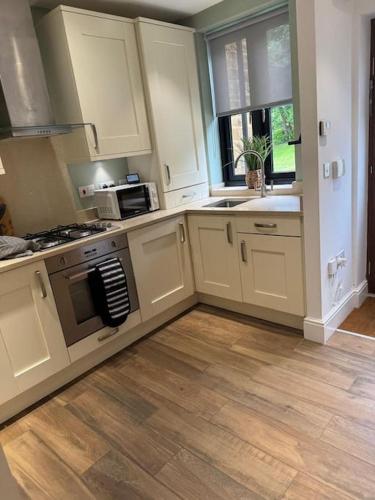 a kitchen with white cabinets and a wooden floor at Church Court 2 Bed 55 Inch SKY TV Northampton Parking Contractor Accommodation in Earls Barton