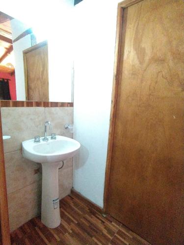 a bathroom with a white sink and a wooden door at Cabañas LA BUENA FE in La Falda
