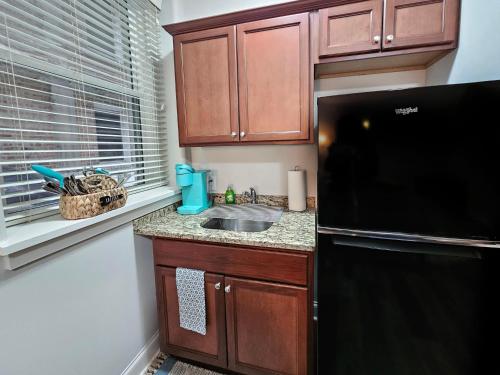a kitchen with a sink and a black refrigerator at Cute + Cozy Studio at The Inman - 207 in Champaign