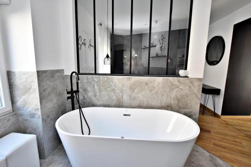 Un baño con bañera blanca y lavabo. en Suite Arum classée 3 étoiles avec terrasse, en Roanne