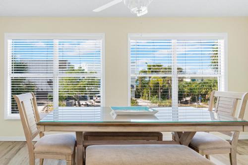 a dining room with a glass table and two windows at Living the Dream By Beachside Management in Siesta Key