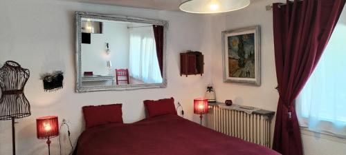a bedroom with a red bed and a mirror at La Casanat in Montgiscard