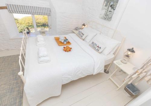 a white bedroom with a white bed and a window at Coast Barn, Noss Mayo, Plymouth in Plymouth