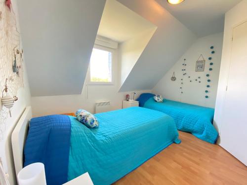 - 2 lits dans une chambre avec des draps bleus dans l'établissement Pen Ar Pont, à Cléder