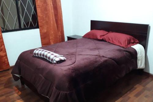 a bedroom with a large bed with red and white pillows at Departamento Monay 1 in Cuenca