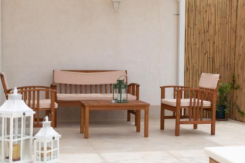 a patio with wooden furniture and a table and chairs at Lu Mari Rooms in Marina di Ragusa