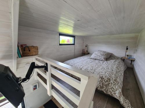 a bedroom in a tiny house with a bed at Tiny House in Varneville-Bretteville
