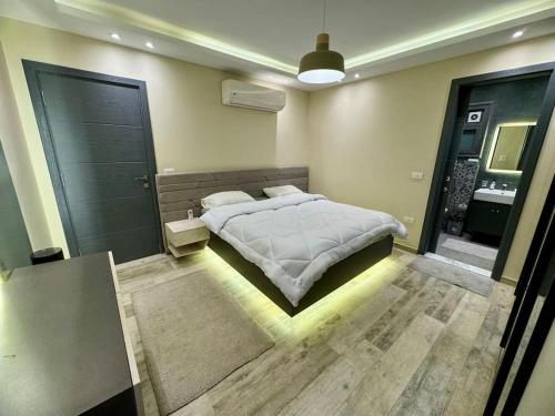 ein Schlafzimmer mit großem Bett und ein Badezimmer in der Unterkunft Charming Luxury Apartment - New Cairo in Kairo