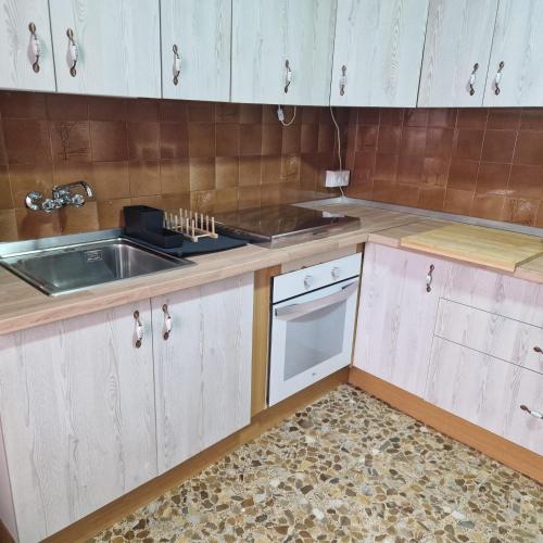 a kitchen with white cabinets and a sink at Piso del Balcón in Cazorla