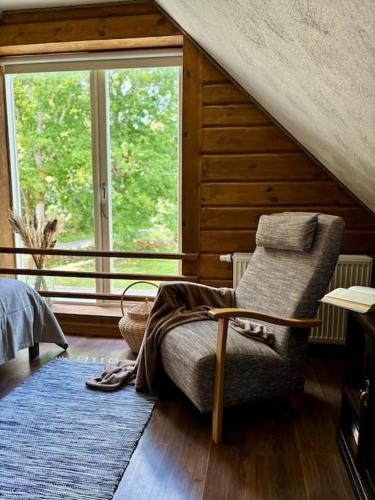 a bedroom with a chair and a large window at Mailase Puhkemaja saunaga in Mõisaküla