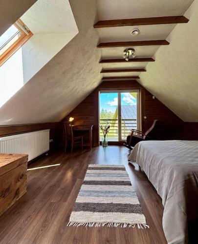a attic bedroom with a bed and a large window at Mailase Puhkemaja saunaga in Mõisaküla
