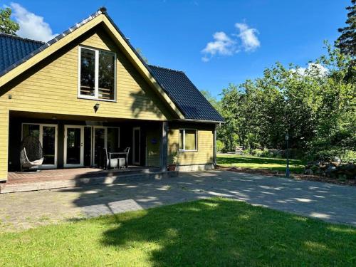 a yellow house with a driveway in the yard at Mailase Puhkemaja saunaga in Mõisaküla