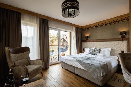 a bedroom with a bed and a chair and a window at Aparthotel Merynos in Zakopane