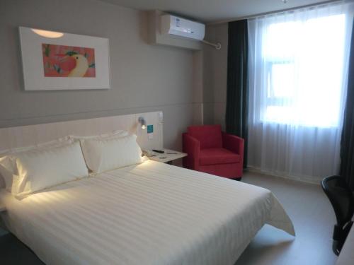 a bedroom with a white bed and a red chair at Jinjiang Inn Linyi South Suhe Road in Linyi