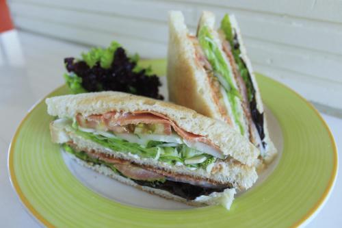 a sandwich is cut in half on a green plate at Hotel Ibis Semarang Simpang Lima in Semarang