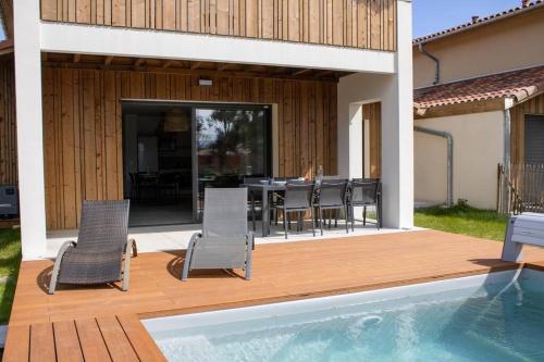 un patio avec une table et des chaises et une piscine dans l'établissement Le Cottage Des Glycines - Piscine chauffée, à Moliets-et-Maa
