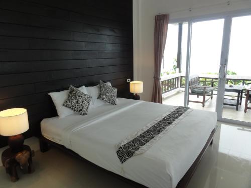 a bedroom with a large bed and a balcony at High Life Bungalow in Haad Yao