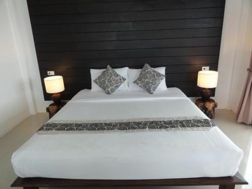 a bedroom with a large white bed with two lamps at High Life Bungalow in Haad Yao